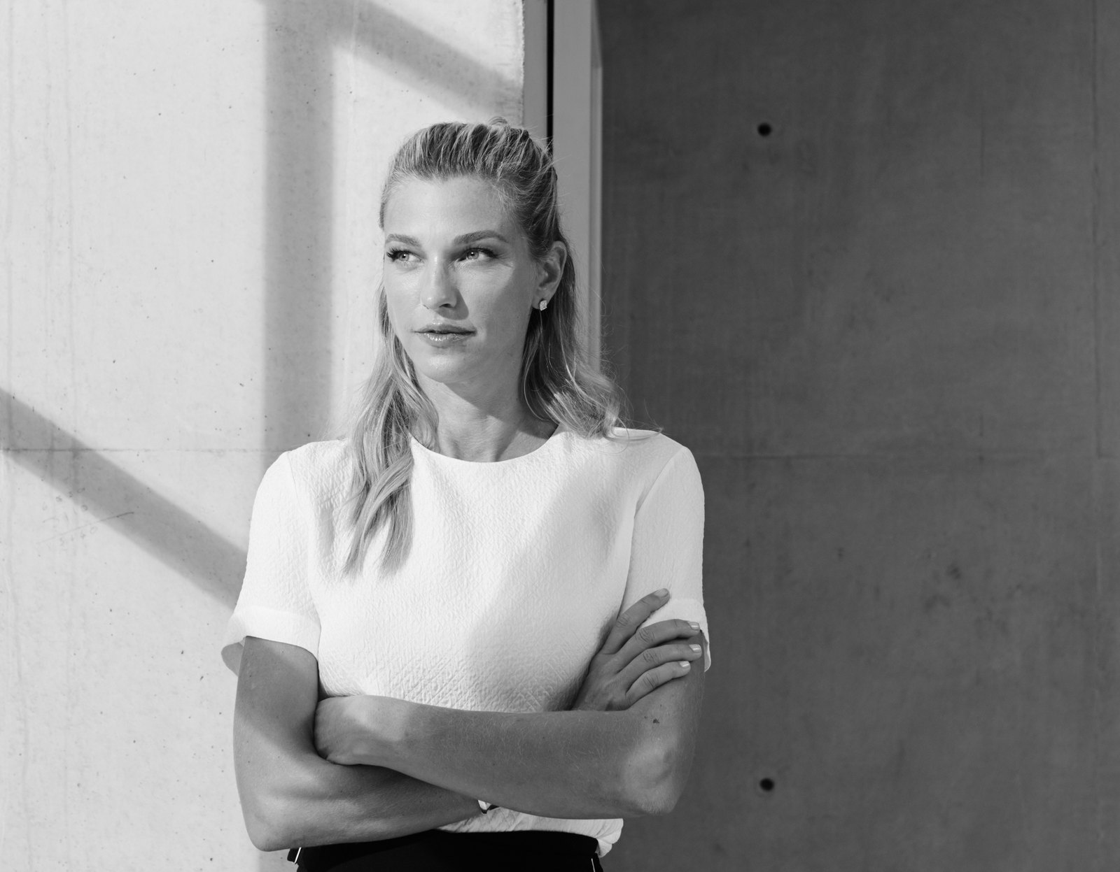 Nicole Junkerman standing thoughtfully against a concrete wall