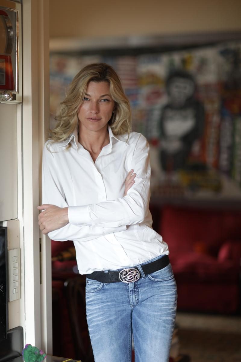 Nicole Junkerman relaxed at home in a white shirt and jeans, beside colourful modern art
